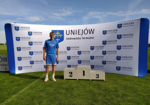 uczeń w niebieskim stroju sportowym przy podium pod ścianką miejscowości Uniejów